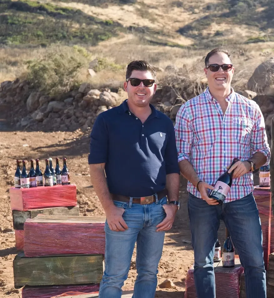 Dave Phinney and Art Sutley standing outdoors together with bottles of Eight Years in the Desert wine