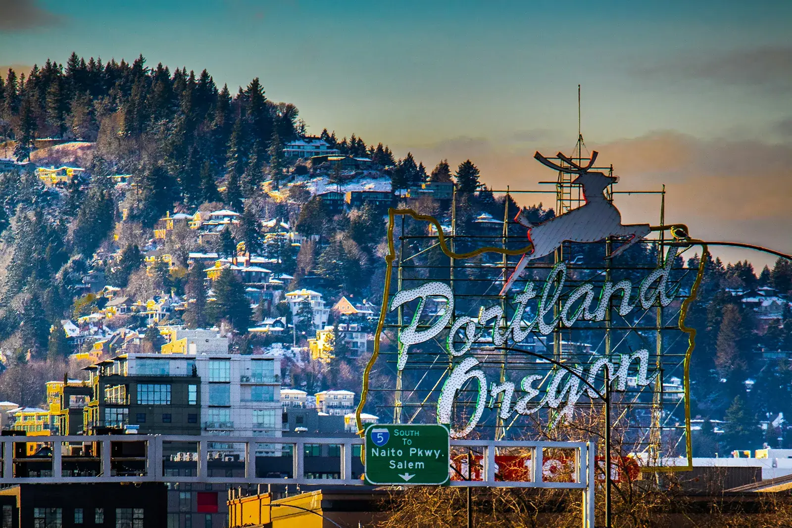 The Portland Oregon White Stag sign in front of the snowy West Hills