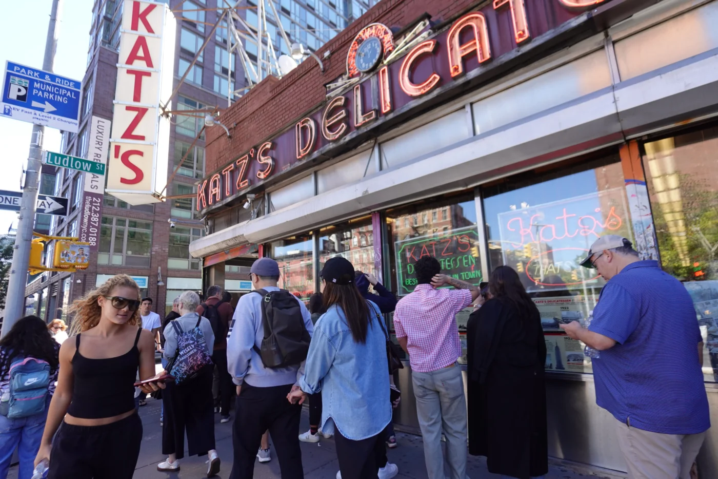 Crowd gathered outside the iconic red neon sign of Katz's Delicatessen on Ludlow Street in NYC.